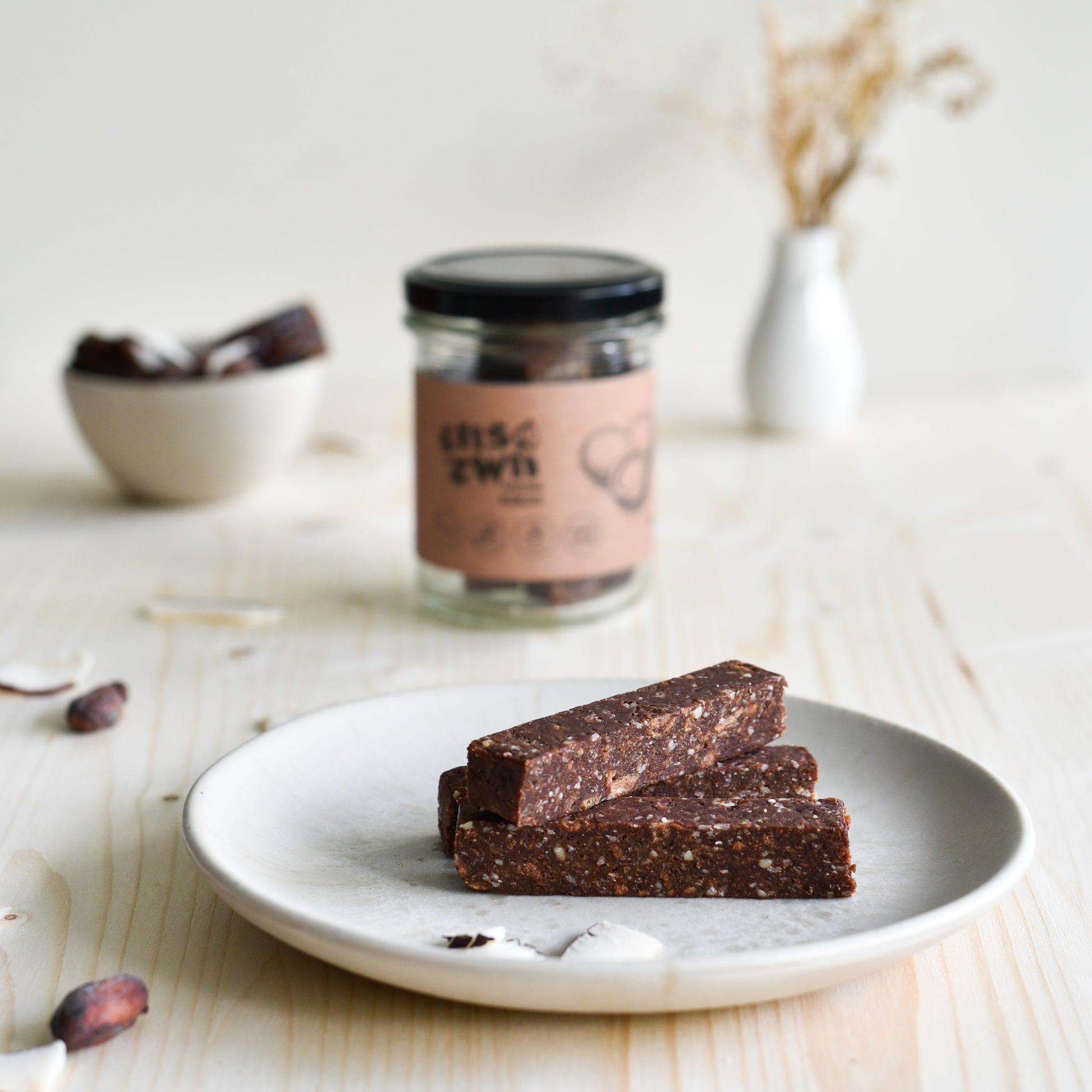 Veganer Kokosriegel einzeln und im Glas präsentiert, natürlich süss und ohne Zuckerzusatz, handgemacht in der Schweiz.