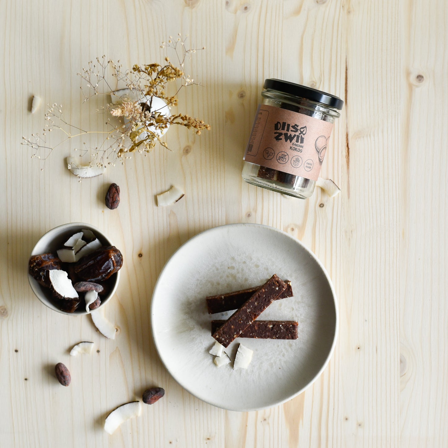 Veganer Kokosriegel einzeln und im Glas präsentiert, natürlich süss und ohne Zuckerzusatz, handgemacht in der Schweiz.