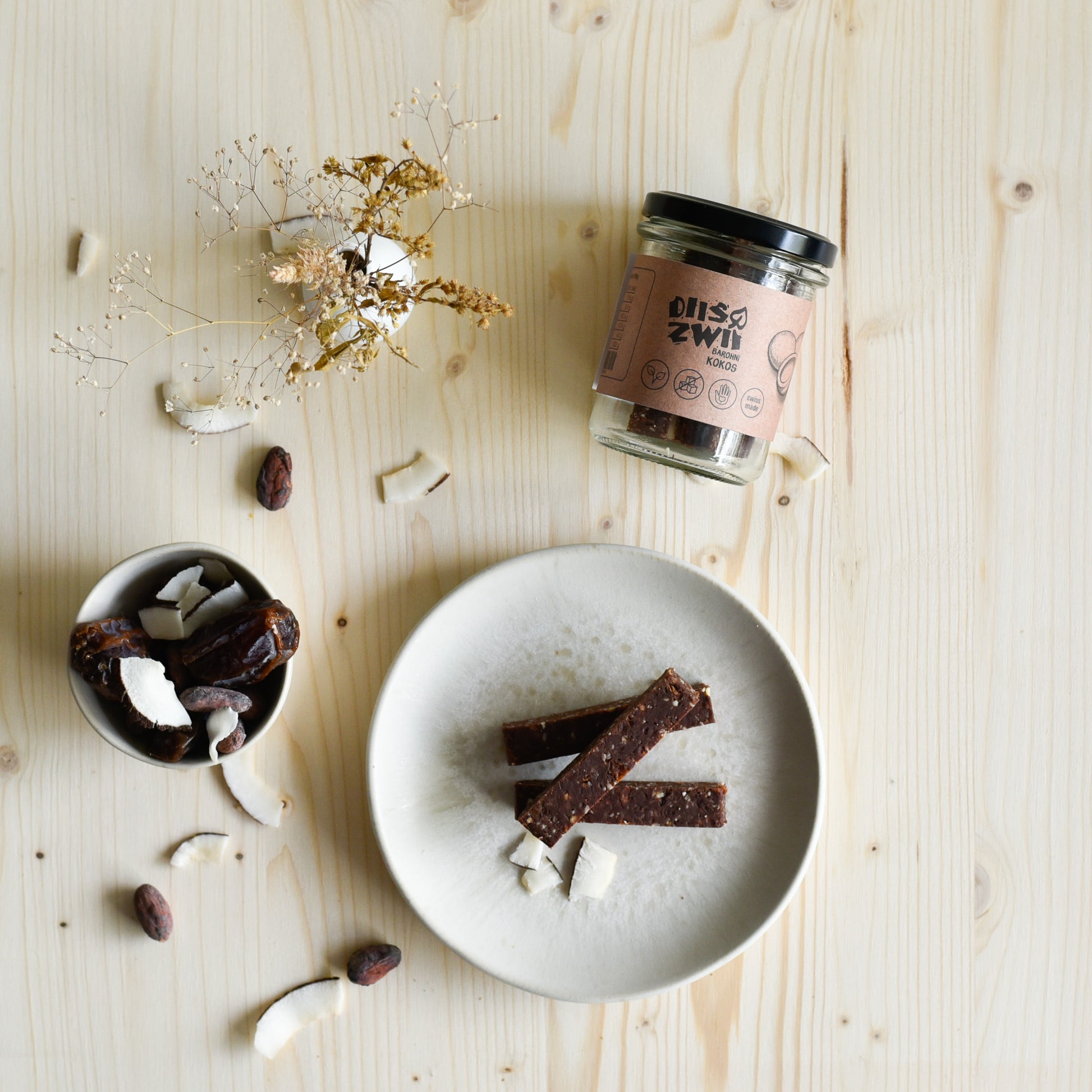 Veganer Kokosriegel einzeln und im Glas präsentiert, natürlich süss und ohne Zuckerzusatz, handgemacht in der Schweiz.